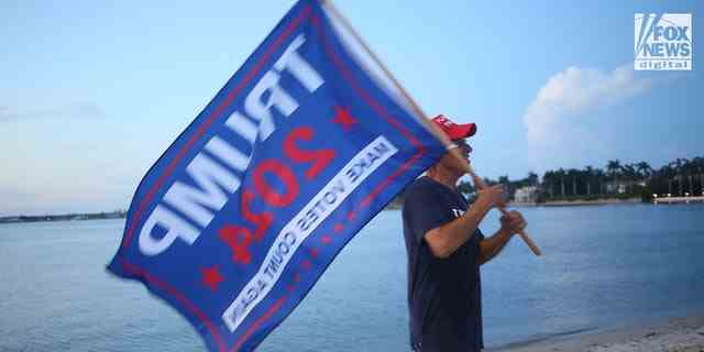 Ein Mann mit einer Trump 2024-Flagge ist außerhalb von Mar-a-Lago in Palm Beach, Florida, nach einer FBI-Razzia in Donald Trumps Privathaus abgebildet.