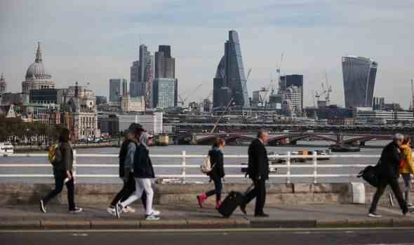 Fußgänger zu Fuß über die Waterloo Bridge mit der Skyline der City of London im Hintergrund