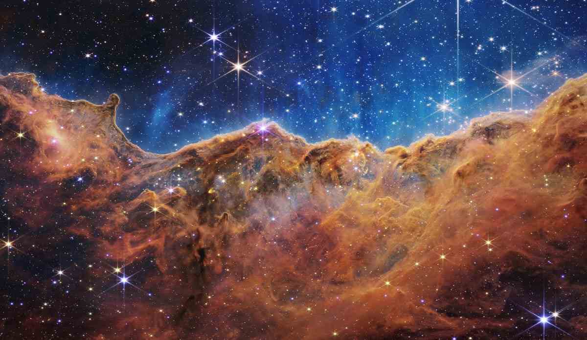 Carina-Nebel: Sterne funkeln vor einem indigoblauen Hintergrund über rostigen bronzenen Gaswolken