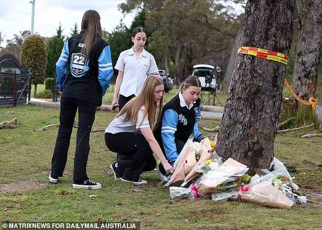 Four schoolgirls laid bunches of flowers at the base of a tree at the crash site on Wednesday