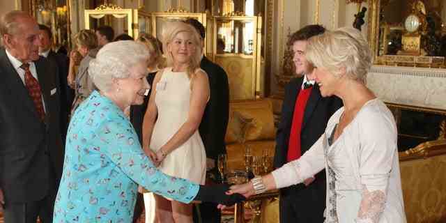 Queen Elizabeth II. schüttelte Dame Dame Helen Mirren die Hand, während Sängerin Ellie Goulding bei einem Empfang zuschaute, um junge Menschen in den darstellenden Künsten im Buckingham Palace im Jahr 2011 zu feiern.