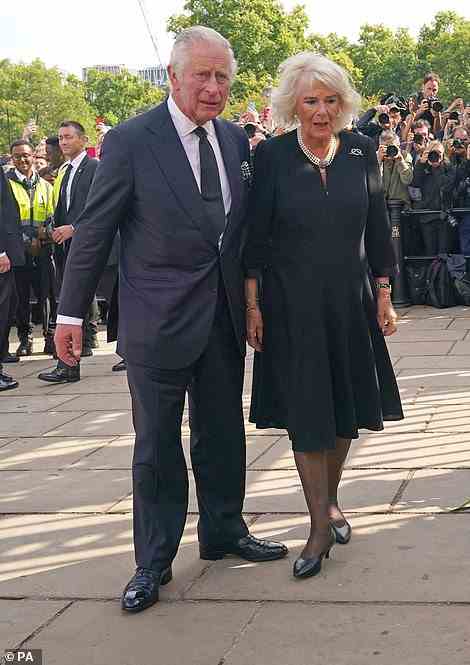 The new King places his arm around Camilla as they walk pass photographers towards the gates of the palace