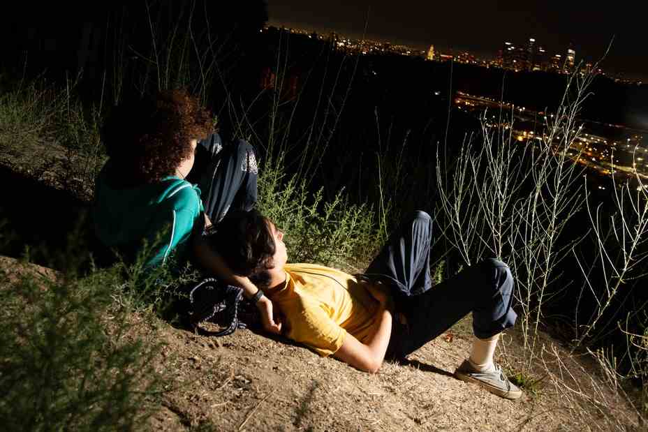 Ein junges Paar, das auf dem Boden liegt, blickt auf die Lichter der Stadt