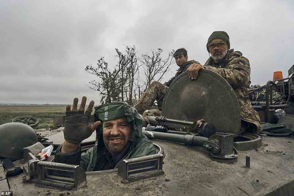 A Ukrainian soldier smiles from a military vehicle on the road in the freed territory in the Kharkiv region, Ukraine