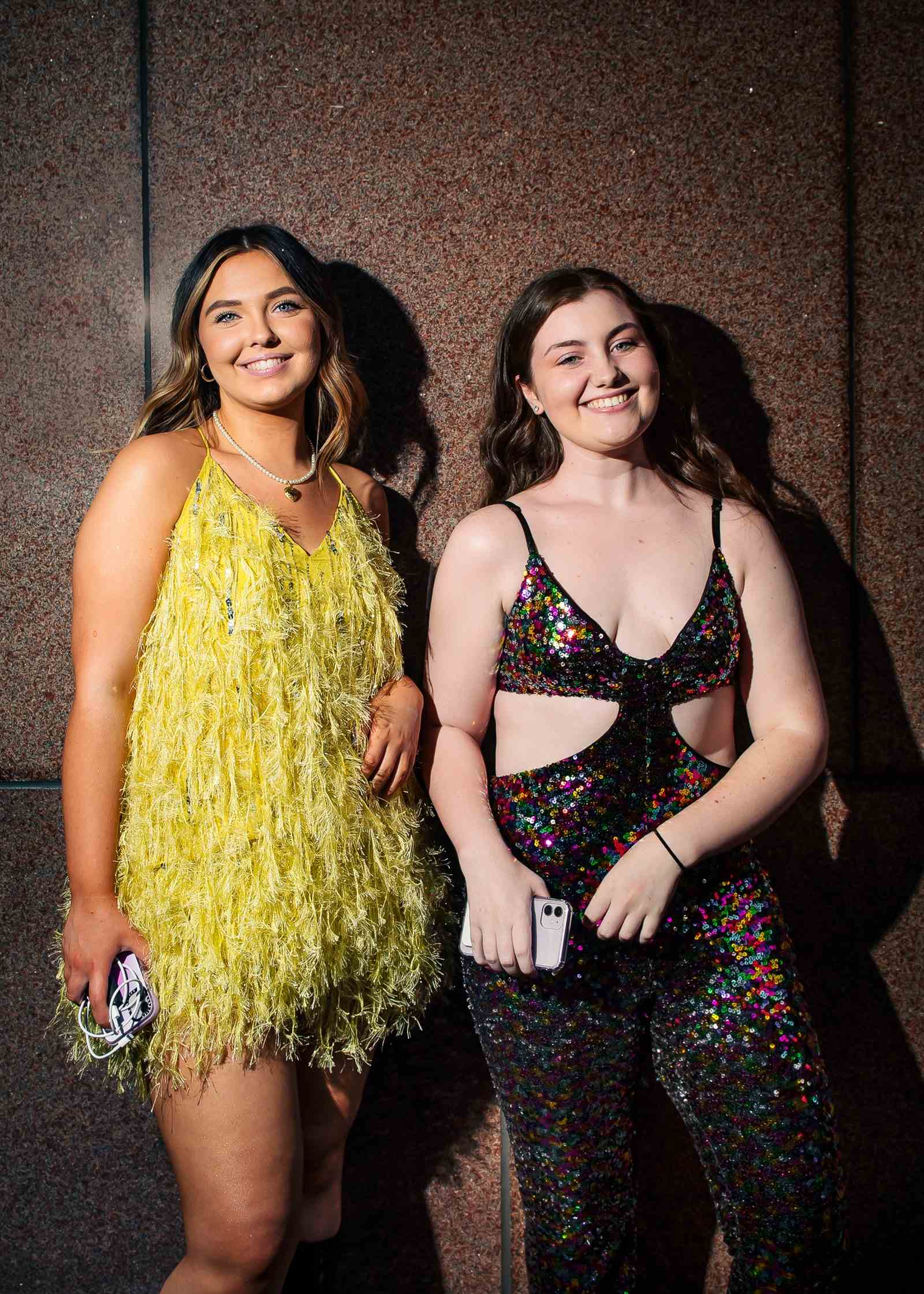 Zwei Frauen stehen an einer Wand vor dem Madison Square Garden.  Die Frau links trägt ein gelbes Federkleid...