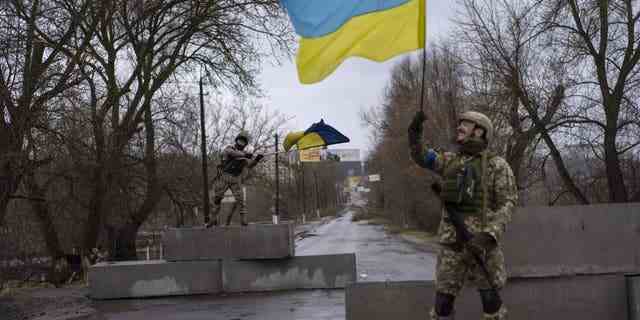 Ukrainische Soldaten feiern am Sonntag, den 3. April 2022, an einem Kontrollpunkt in Bucha am Stadtrand von Kiew, Ukraine. 