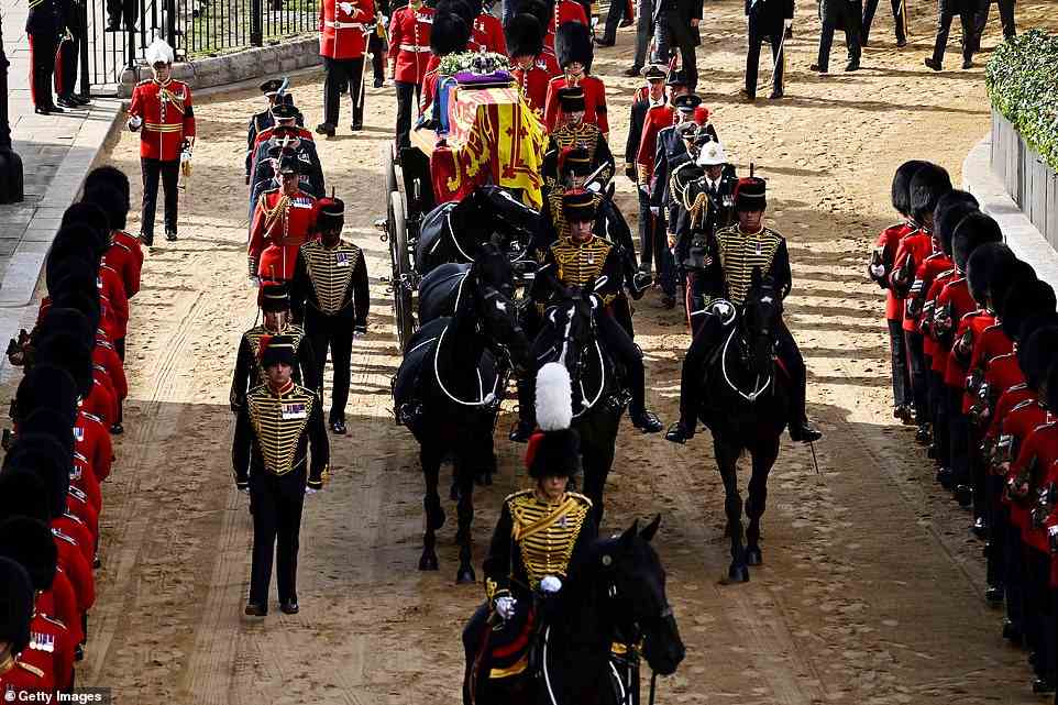 The coffin of Queen Elizabeth II, adorned with a Royal Standard and the Imperial State Crown and pulled by a Gun Carriage of The King's Troop Royal Horse Artillery, arrives at the Palace of Westminster