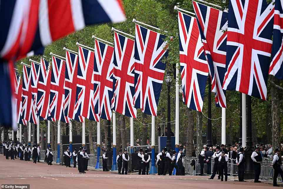 Union flags are seen lining The Mall today as Metropolitan Police officers are seen gathering ahead of the procession