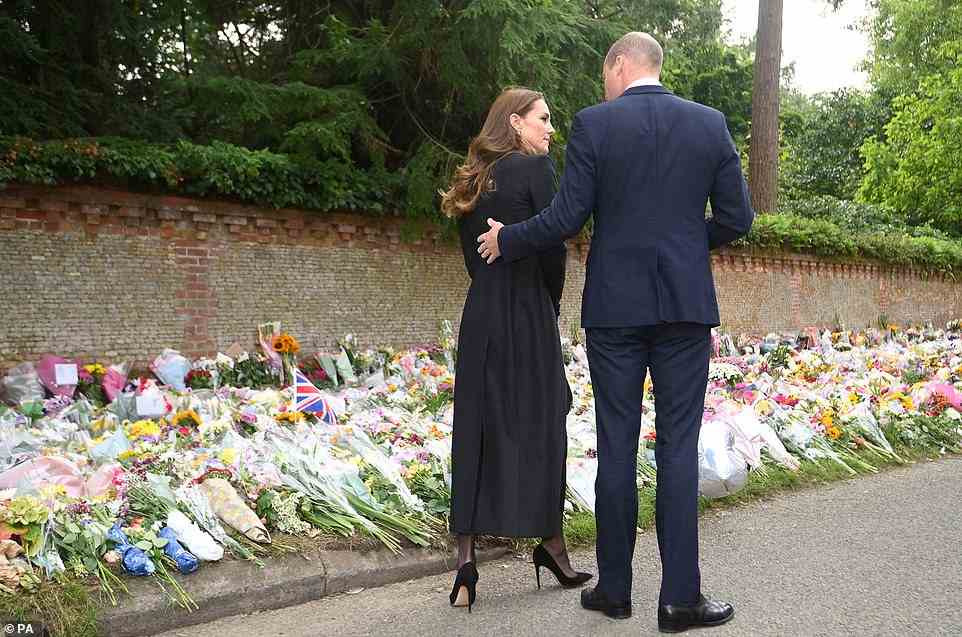 Prince William gently touches Kate's back as they inspect the sea of flowers left in memory of Queen Elizabeth II