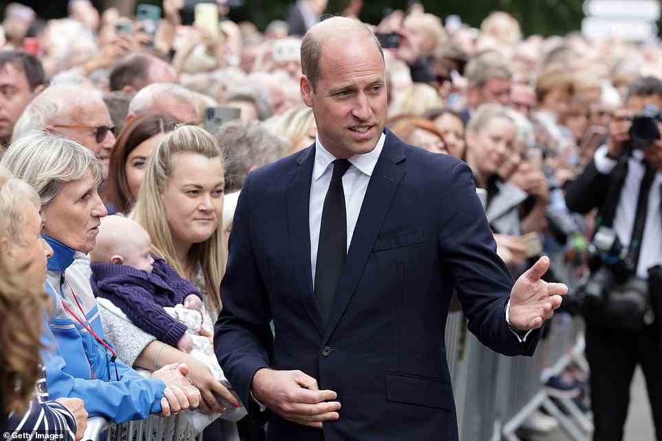 William gestures as a woman holding a baby watches on at Sandringham today