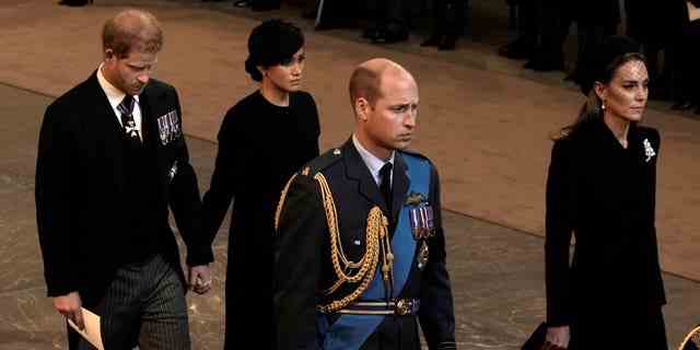 Prinz William und Kate Middleton führen die Prozession an, während der Sarg von Königin Elizabeth II. Zur Westminster Hall transportiert wird, während Prinz Harry und Meghan Markle in der Ferne stehen.