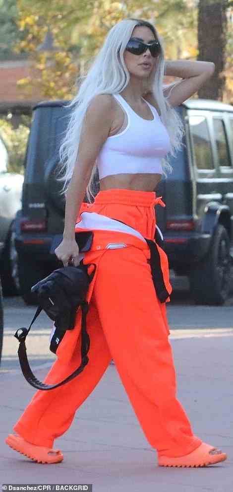 Lässiger Stil: Kim zeigte ihre getönten Bauchmuskeln und trat in einer großen dunklen Sonnenbrille und orangefarbenen Slide-Sandalen aus