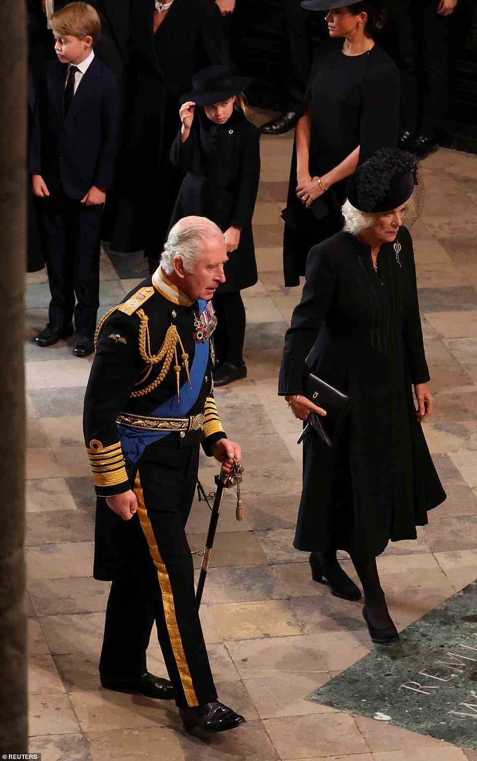 King Charles III and the Queen Consort looked grave as they walked in unison to the front row, to take their seat ahead of the ceremony