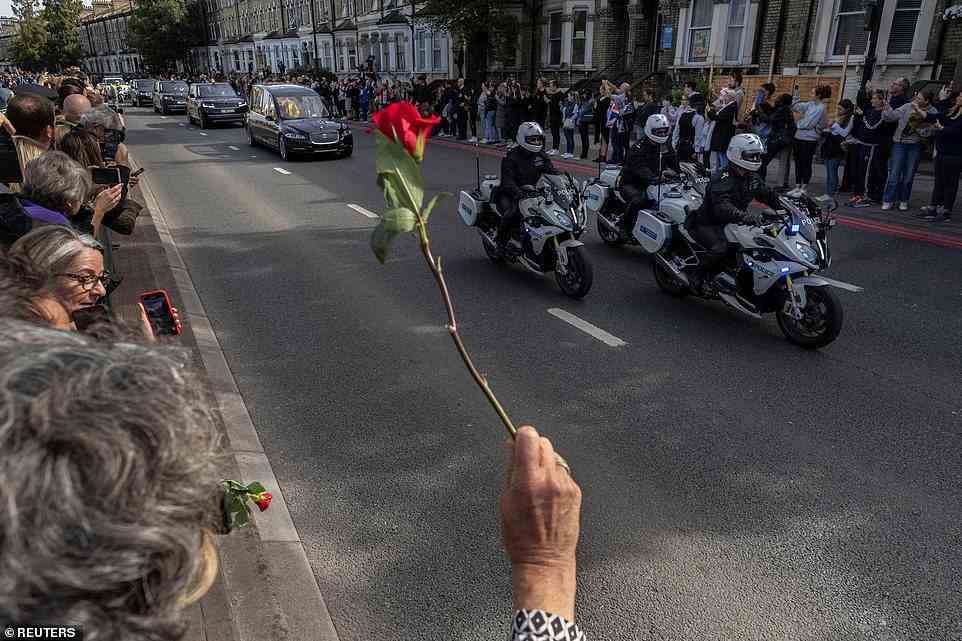 A person holds a rose to throw, as Britain's Queen Elizabeth's coffin is transported, on the day of her state funeral and burial