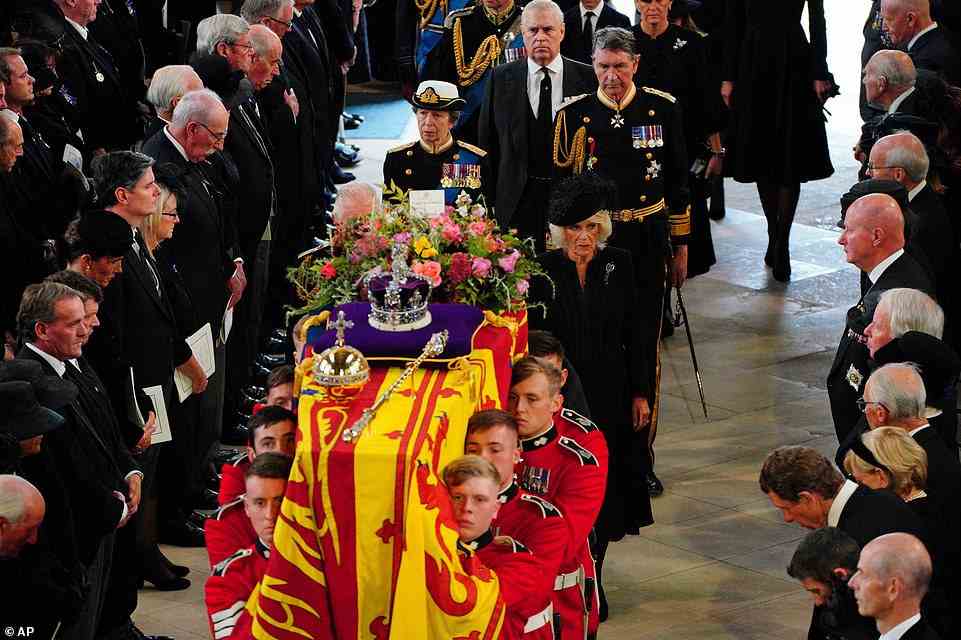 The Queen's final resting place will be alongside her beloved husband Prince Philip in Windsor's St George's Chapel this evening. Above: The Queen's coffin is carried into St George's Chapel this afternoon