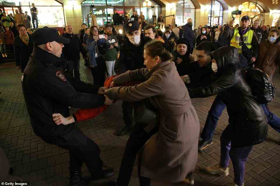 Russian police officers try to detain a protester during an anti-war protest in Moscow tonight, with other activists trying to pull them away