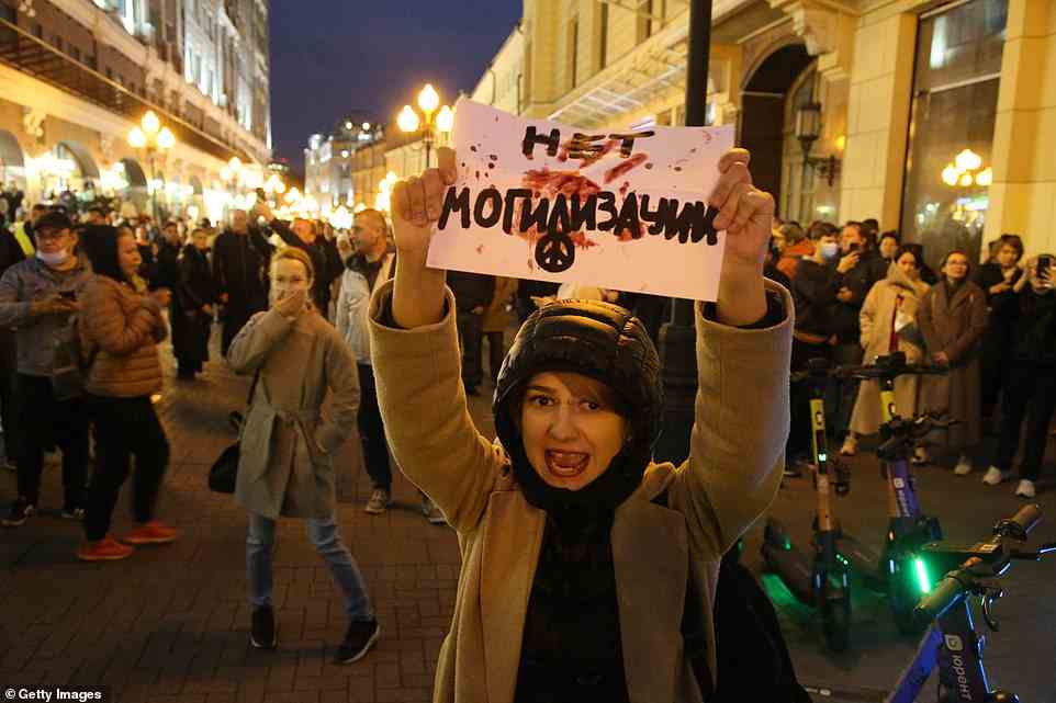 A female activist holds an anti-mobilisation poster and shouts slogans during a protest in Arbat Street, Moscow, earlier tonight