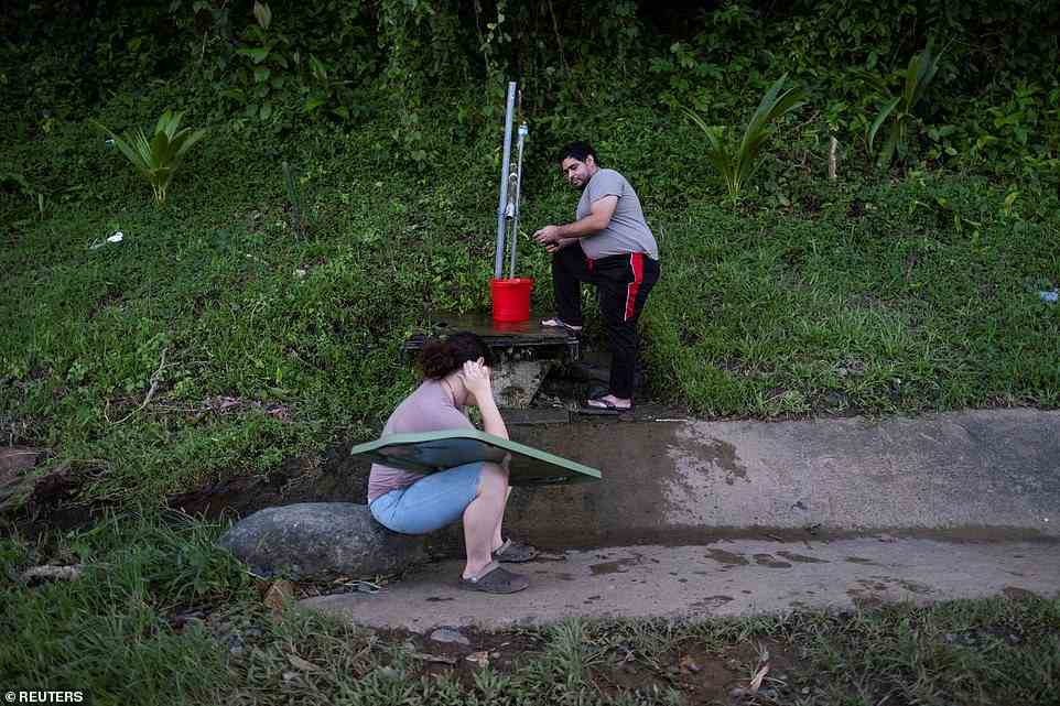 A man collects spring water from a mountain next to a highway in the aftermath of Hurricane Fiona in Cayey, Puerto Rico