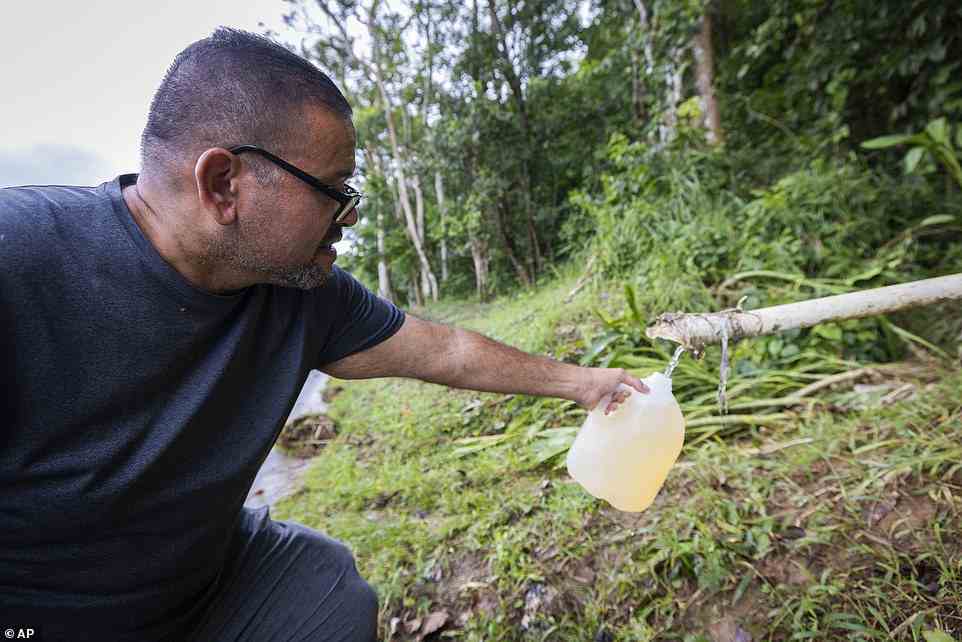 A man collects spring water from a mountain in Cayey, Puerto Rico on Tuesday