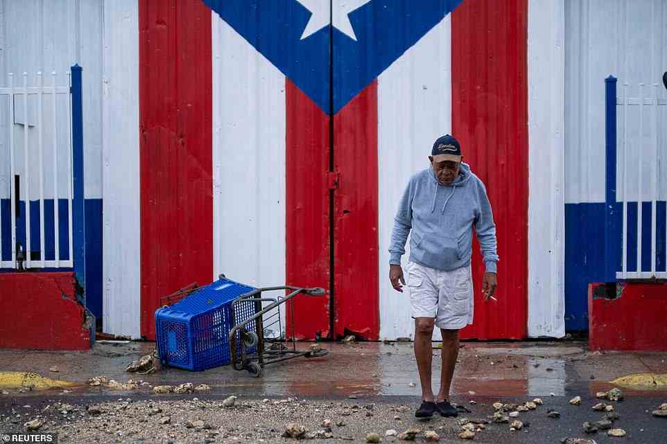A man walks pass by a Puerto Rican flag painted on a door in the aftermath of Hurricane Fiona in Penuelas, Puerto Rico