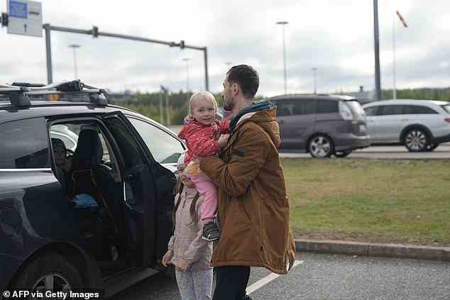 Viktor Zakarov, a 35-year-old scientist from Saint Petersburg, holds one of his three children after passing the passport check