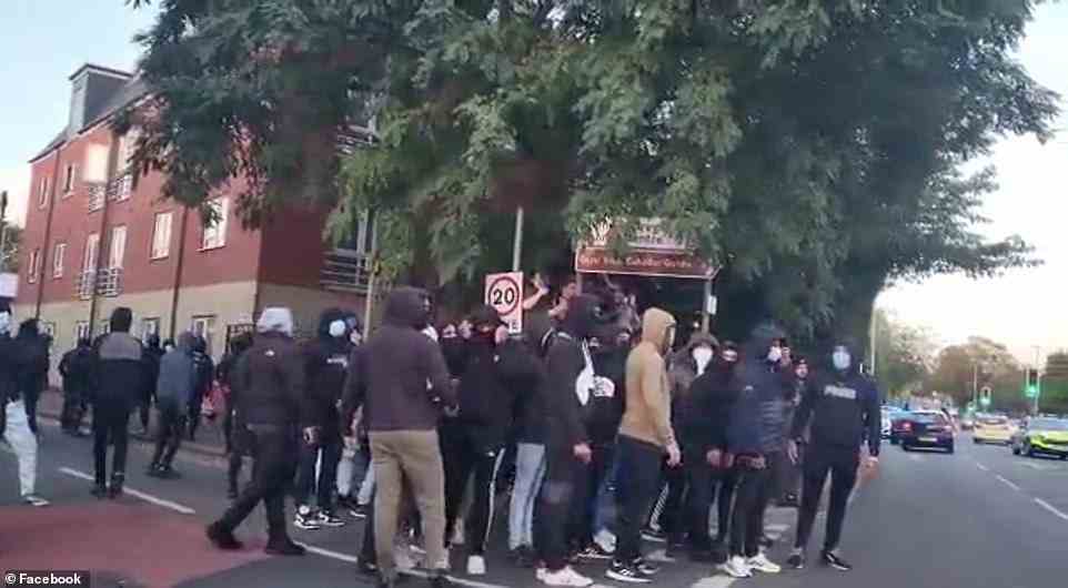 A group of masked men march through Leicester on Sunday with one seen armed with a 2x4 foot piece of wood amid violent clashes between Hindus and Muslims