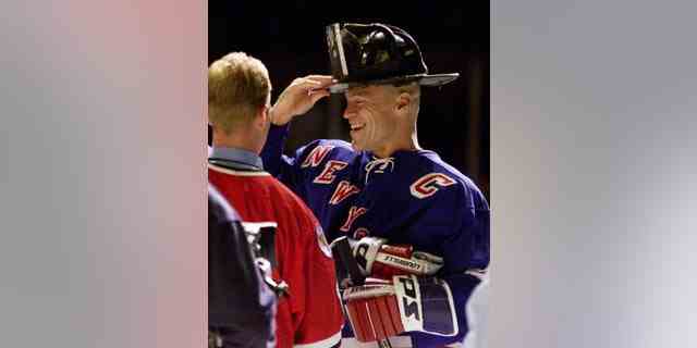 Der Kapitän der New York Rangers, Mark Messier, setzt am 7. Oktober 2001 im Madison Square Garden den Helm des Fire Department Chief of Special Operations Command Ray Downey auf. 