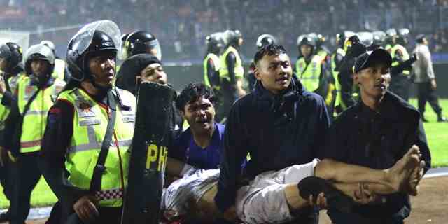 Fußballfans tragen einen verletzten Mann.  Bei Zusammenstößen zwischen Anhängern zweier indonesischer Fußballmannschaften in der Provinz Ostjava wurden über 100 Fans und eine Reihe von Polizisten getötet, die größtenteils zu Tode getrampelt wurden, teilte die Polizei am Sonntag mit.