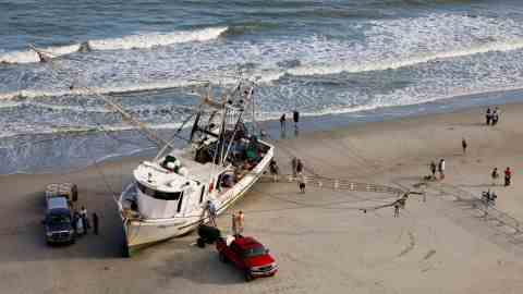 Arbeiter und Besitzer eines großen Krabbenkutters bereiten ihr Schiff darauf vor, es am Samstag wieder ins Wasser zu schleppen, nachdem es in Myrtle Beach, South Carolina, an Land gespült wurde.