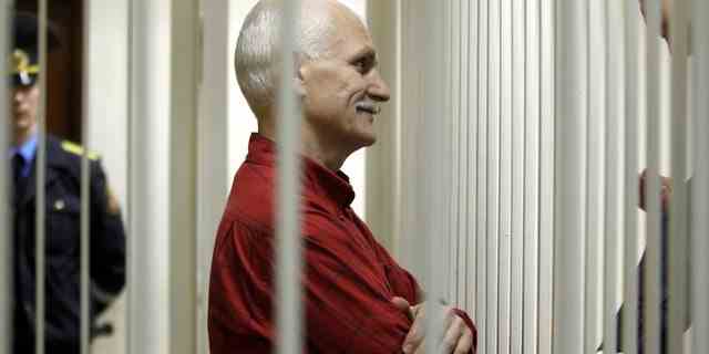 Ales Belyatsky, der inhaftierte Anführer von Vesna, der bekanntesten Menschenrechtsgruppe in Weißrussland, winkt seinen Verwandten zu, während er während einer Gerichtsverhandlung in Minsk, Weißrussland, am Donnerstag, den 24. November 2011, in einem Käfig sitzt. 