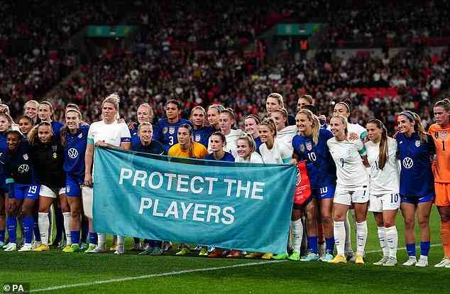 England and USA stand together in the center circle with a banner which reads "Protect the Players" as a show of solidarity for the victims of sexual abuse before the international friendly match at Wembley Stadium, London on Friday