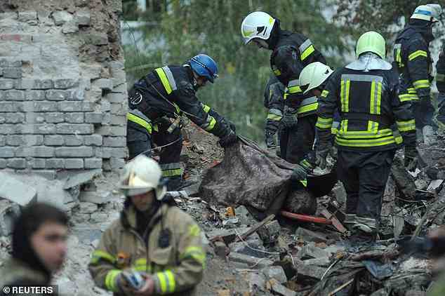 Während Putins Bombardierung der Ukraine weitergeht, bedecken Feuerwehrleute den Leichnam eines Mannes, der über Nacht durch russischen Beschuss der Stadt Saporischschja getötet wurde, mit einem Laken