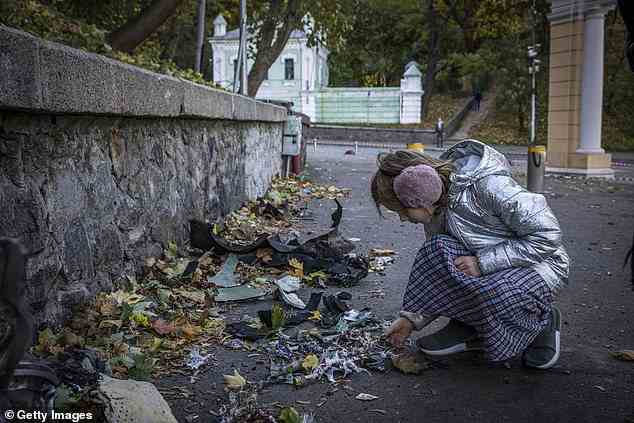 Ein junges Mädchen betrachtet mutmaßliche Trümmer einer Rakete am Ort einer Explosion bei einer Fußgängerbrücke mit Blick auf den Fluss Dnipro in Kiew
