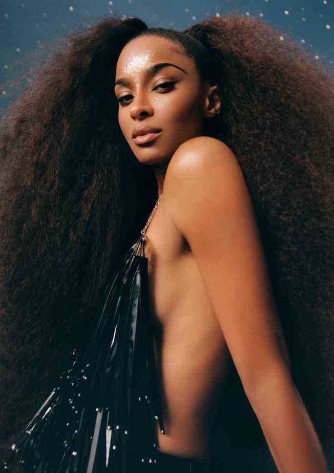 Portrait of Ciara for Allure Magazine. She is sitting on the floor looking over her shoulder into the camera, wearing a black, backless top and her hair pulled into two long, curly ponytails. 