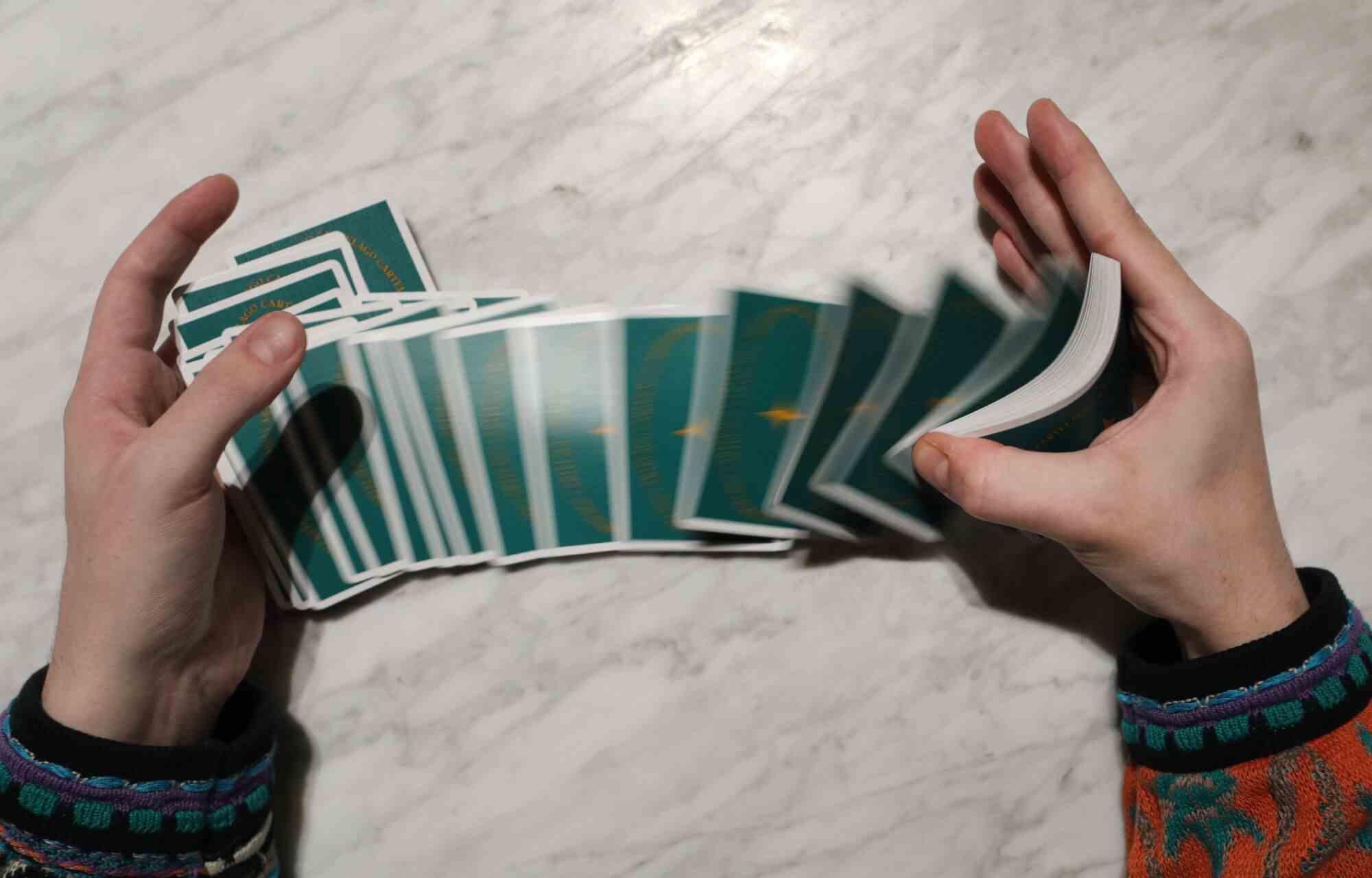 Eine Person mischt ein Kartenspiel von einer Hand in die andere.