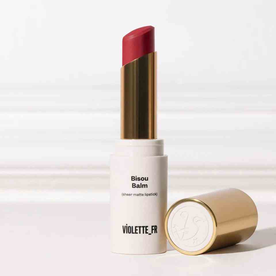 Violette_Fr Bisou Balm Gold und weiße Tube mit rosa Lippenstift im Reinraum