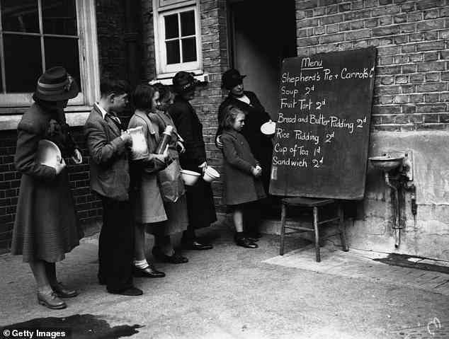 Die Gemeinschaftsküchen-Initiative wurde zuerst von Lord Woolton, Ernährungsminister während des Krieges, angeführt, um die Gesundheit und Stärke der Nation während des Zweiten Weltkriegs zu stärken.  Im Bild: Menschen, die sich 1940 eine Speisekarte vor einem britischen Restaurant ansehen