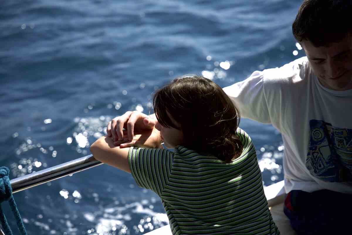 Ein Mädchen lehnt am Rand eines Bootes und stützt sich auf den Arm ihres Vaters 