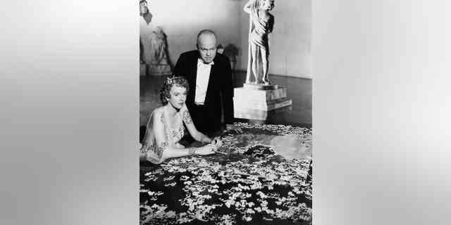 Charles Foster Kane (Orson Welles) steht über seiner zweiten Frau Susan Alexander Kane (Dorothy Comingore), während sie ein Puzzle zusammensetzt "Citizen Kane." Viele glaubten, dass die Rolle von Alexander von Marion Davies inspiriert wurde.