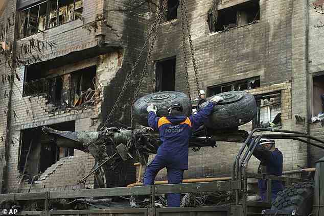 Emergency workers load debris of a warplane on a truck at the scene of a plane crash in a residential area in Yeysk
