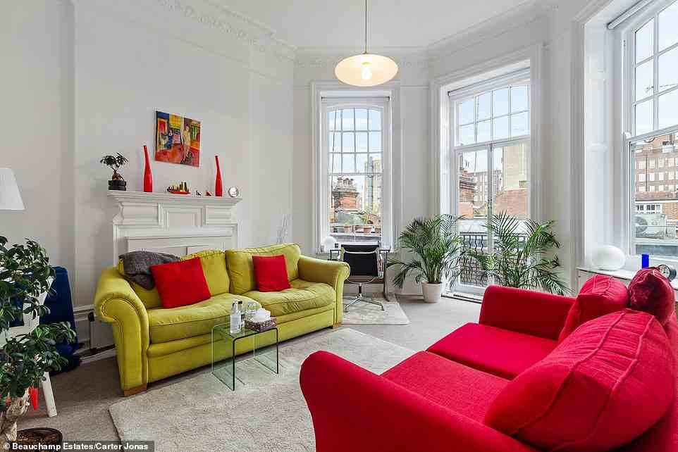 Ein weiterer Blick auf eines der Wohnzimmer, das mit einem hellroten und hellgrünen Sofa ausgestattet ist, die einander zugewandt sind, wenn das Licht von den französischen Türen hereinströmt