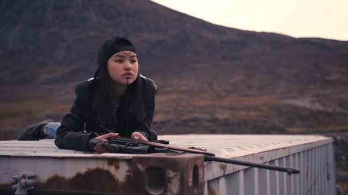 Tasiana Shirley sitzt in einer Szene aus Slash/Back mit einem Gewehr auf einem Schiffscontainer.