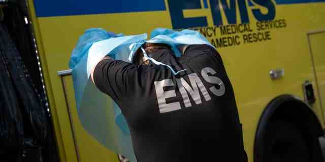 Ein Sanitäter mit Austin-Travis County EMS zieht Schutzkleidung aus, nachdem er einen Mann mit möglichen COVID-19-Symptomen in einen Krankenwagen geladen hat.