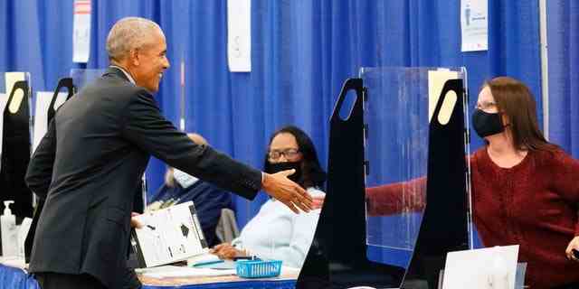Der frühere Präsident Barack Obama schüttelt einem Wahlhelfer die Hand, bevor er am 17. Oktober 2022 in Chicago an einem vorgezogenen Wahlort seine Stimme abgibt.