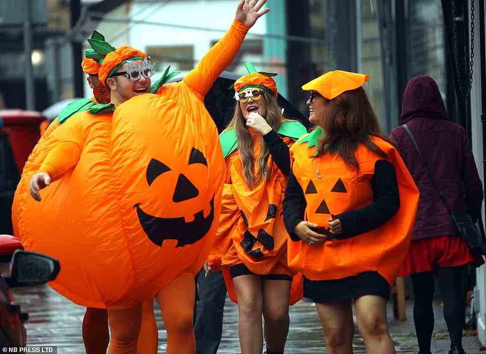 A group dressed as pumpkins walk to a Halloween party in Leeds today despite the heavy rain