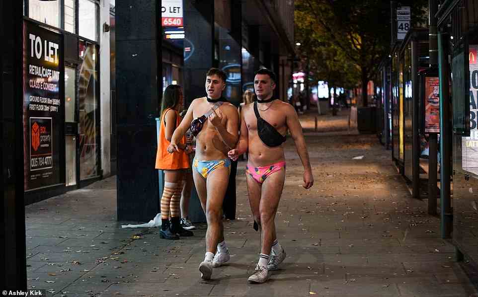 Two men brave the cold in Nottingham wearing only bright-coloured speedos and shoulder bags