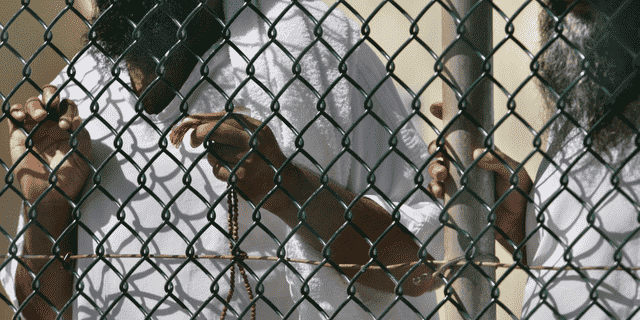 Auf diesem Foto, das von einem Beamten des US-Verteidigungsministeriums begutachtet wurde, stehen Häftlinge im Camp Delta-Gefängnis auf dem US-Marinestützpunkt Guantanamo Bay, Kuba, zusammen an einem Zaun, von denen einer islamische Gebetsketten hält.