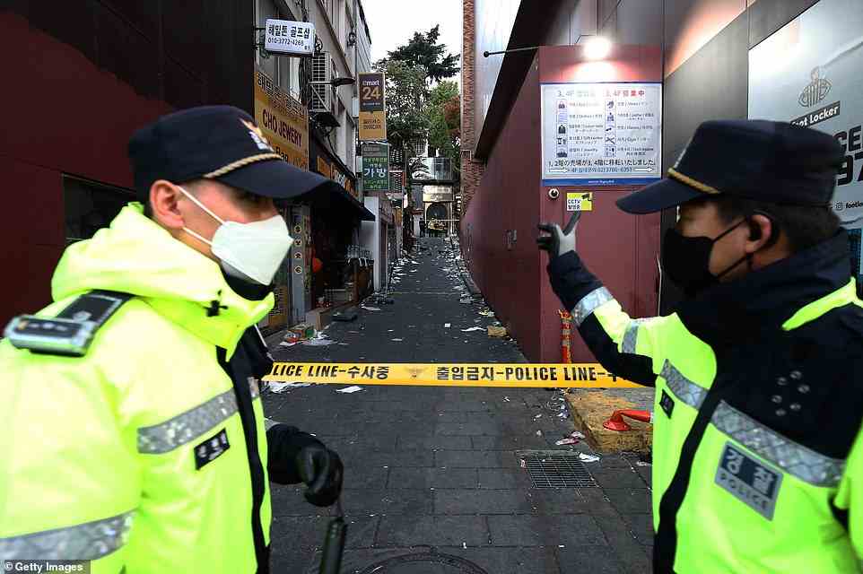 Police officers guard the scene on Sunday morning after thousands became trapped in this tiny alleyway