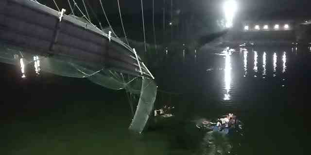 Retter auf Booten suchen im Machchu-Fluss neben einer Kabelbrücke, die am Sonntag, 30. Oktober 2022, im Distrikt Morbi im westlichen Bundesstaat Gujarat, Indien, eingestürzt ist. 