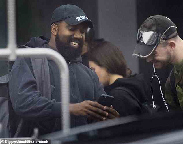 Top of the world: Kanye West, 45, grinste von Ohr zu Ohr über irgendetwas auf seinem Handy, als er am Donnerstag in Los Angeles landete
